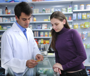 Pharmacist advising client at pharmacy how to take medicine